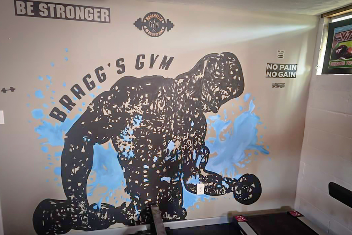 Black silhouette mural of a weightlifter painted on a gym wall