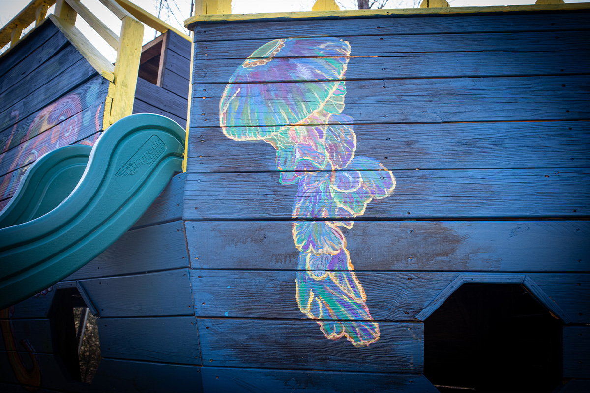Colorful jellyfish mural painted on a wooden outdoor play structure